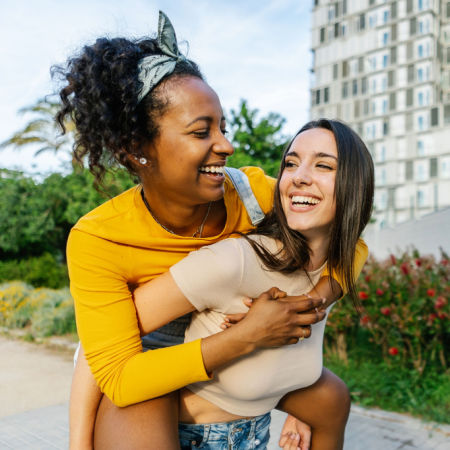 Woman giving girlfriend a piggyback ride