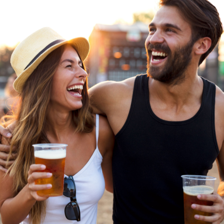 Woman and man holding beers laughing