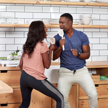 Long-term couple (man and woman) keep the spark alive by singing spontaneously in their kitchen